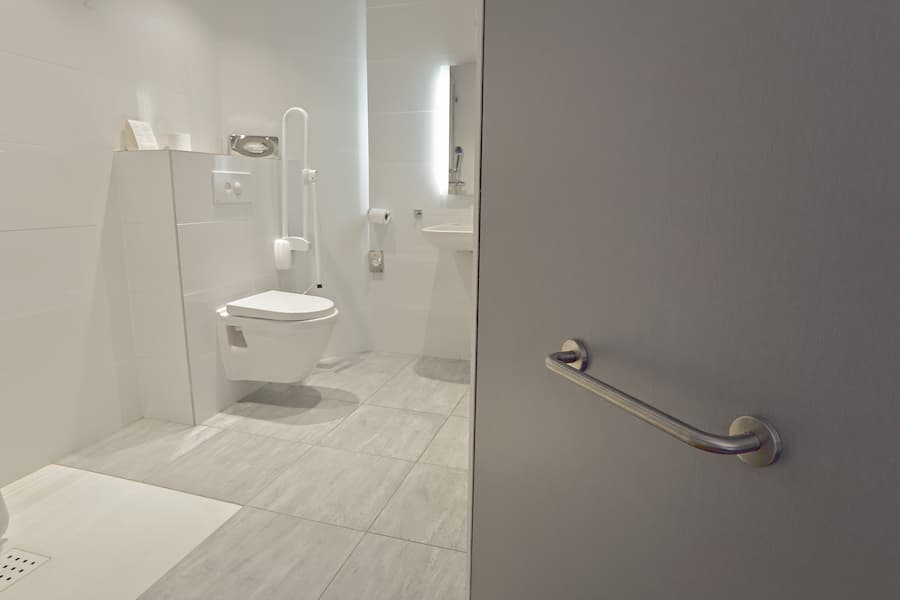 Accessible white bathroom with toilet and handrails
