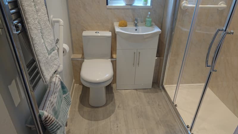 Grey bathroom with walk in shower toilet and sink
